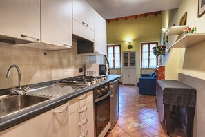 Una cocina con estufa, lavamanos y armarios. Hay un microondas en la encimera.