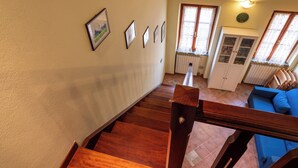 A staircase leading to a living area with a blue sofa, a cabinet, and framed pictures on the wall.