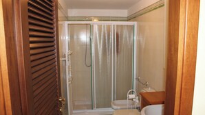 A bathroom with a shower enclosure, toilet, and sink.