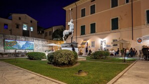 A courtyard with a statue, a mural, and outdoor seating areas.