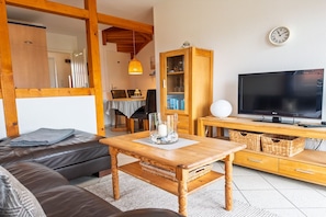 A living room with a sofa, wooden coffee table, television, and a cabinet.
