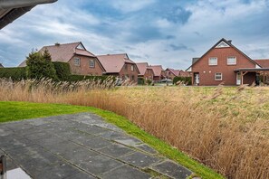 Un barrio residencial con casas de ladrillo, un sendero pavimentado y un campo cubierto de césped.
