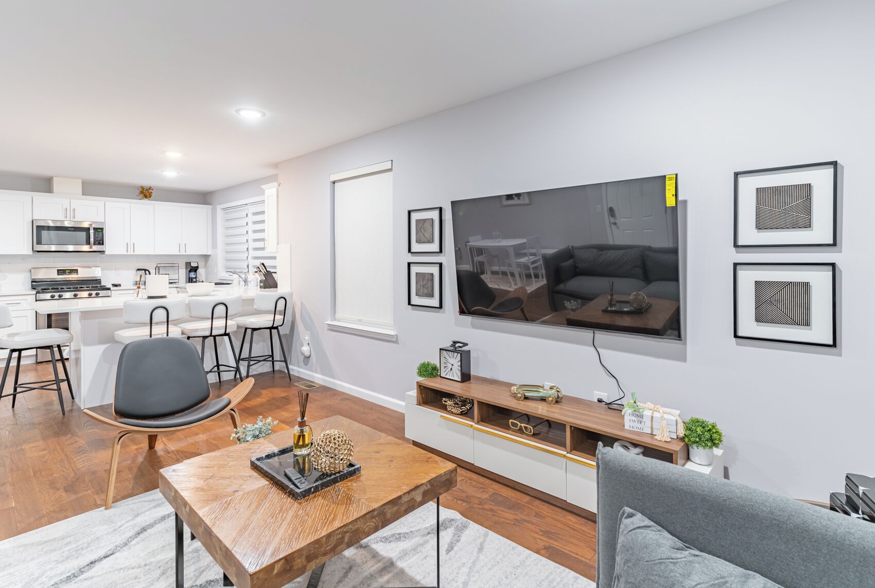 Un salon moderne avec une table basse en bois, un canapé gris et un téléviseur fixé au mur.