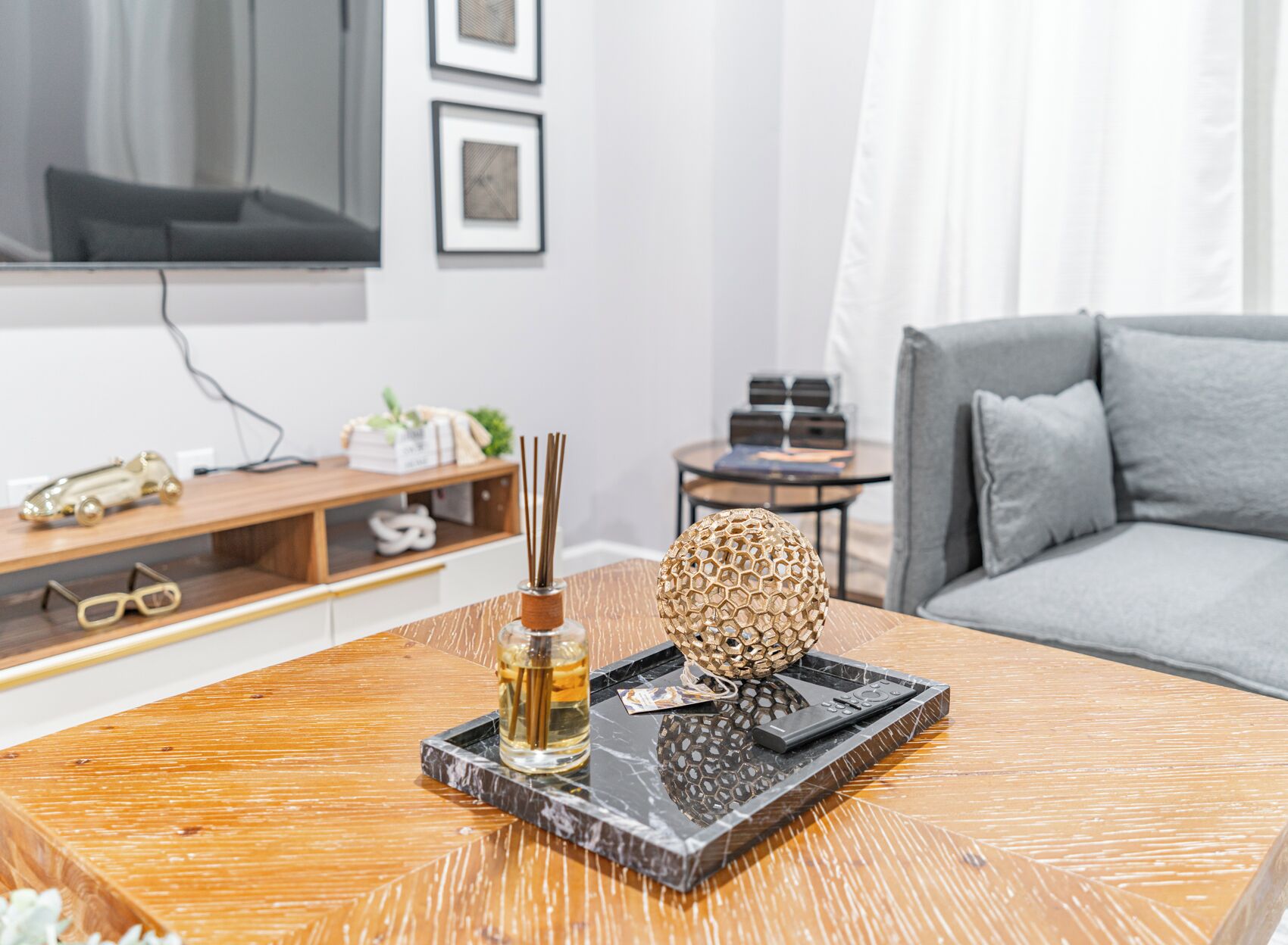 Un salon moderne avec une table basse en bois, une sphère décorative et une bouteille contenant un liquide.