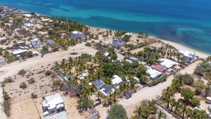 Luchtbeeld van een kustgebied met huizen, palmbomen en een strand.