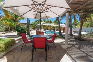 Eine Außenpatio mit Tisch, Stühlen, einem Pool und Palmen.