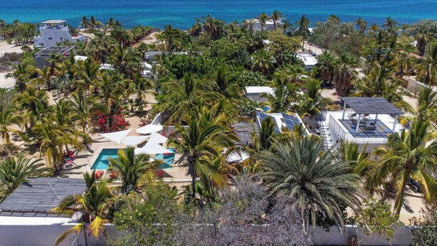 Een resort met een zwembad, palmbomen en uitzicht op de oceaan.