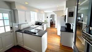 Una cocina moderna con armarios blancos, una isla central y un refrigerador con un letrero.