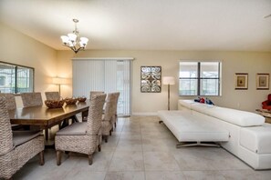 Relax in this inviting living room with a dining table, comfortable sofa, and decorative wall art.