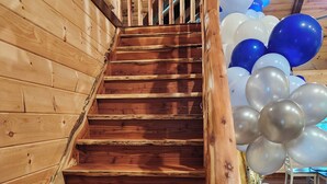 A wooden staircase with a railing, leading to a room decorated with blue and white balloons.