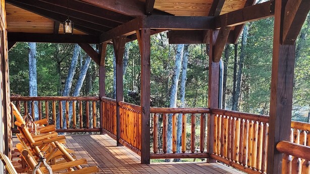 A wooden deck with rows of wooden chairs, a lantern, and a railing.