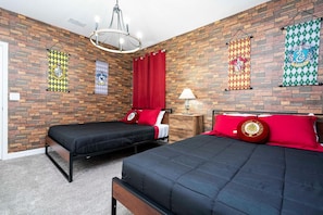 Quarto com duas camas, uma cortina vermelha e um candelabro.