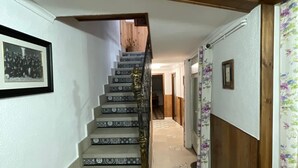 A staircase with patterned tiles, wooden beams, and a framed photograph on the wall. - Rural house los jesuses (Lillo)