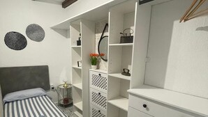A bedroom with a striped bed, a wardrobe with multiple drawers, and a small bedside table with a lamp. - Rural house los jesuses (Lillo)