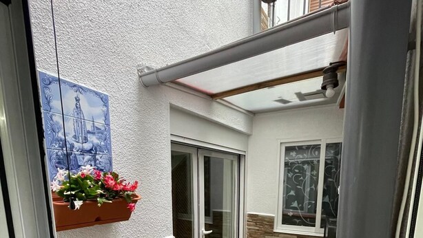 A narrow outdoor corridor with a tiled floor, a sliding glass door, and a window with a decorative frame. - Rural house los jesuses (Lillo)