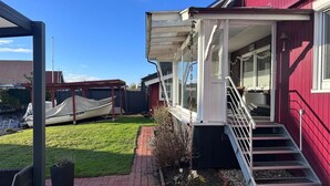 A red building with a covered porch, a staircase, and a grassy yard. - NEW! Vacation home Nordlicht (Südbrookmerland)