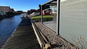 A wooden dock extending into a body of water, with a modern building adjacent to it. - NEW! Vacation home Nordlicht (Südbrookmerland)