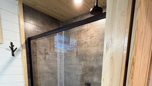 A shower with a glass door, wooden paneling, and a tiled floor. - Sheltered Nook Bunk 'n Board
Farm to Table experience  (Molt)