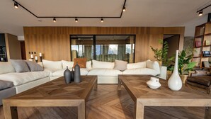 A modern living room with a large sofa, two wooden coffee tables, and a bookshelf. - House by Casa Septem (Tunuyan)