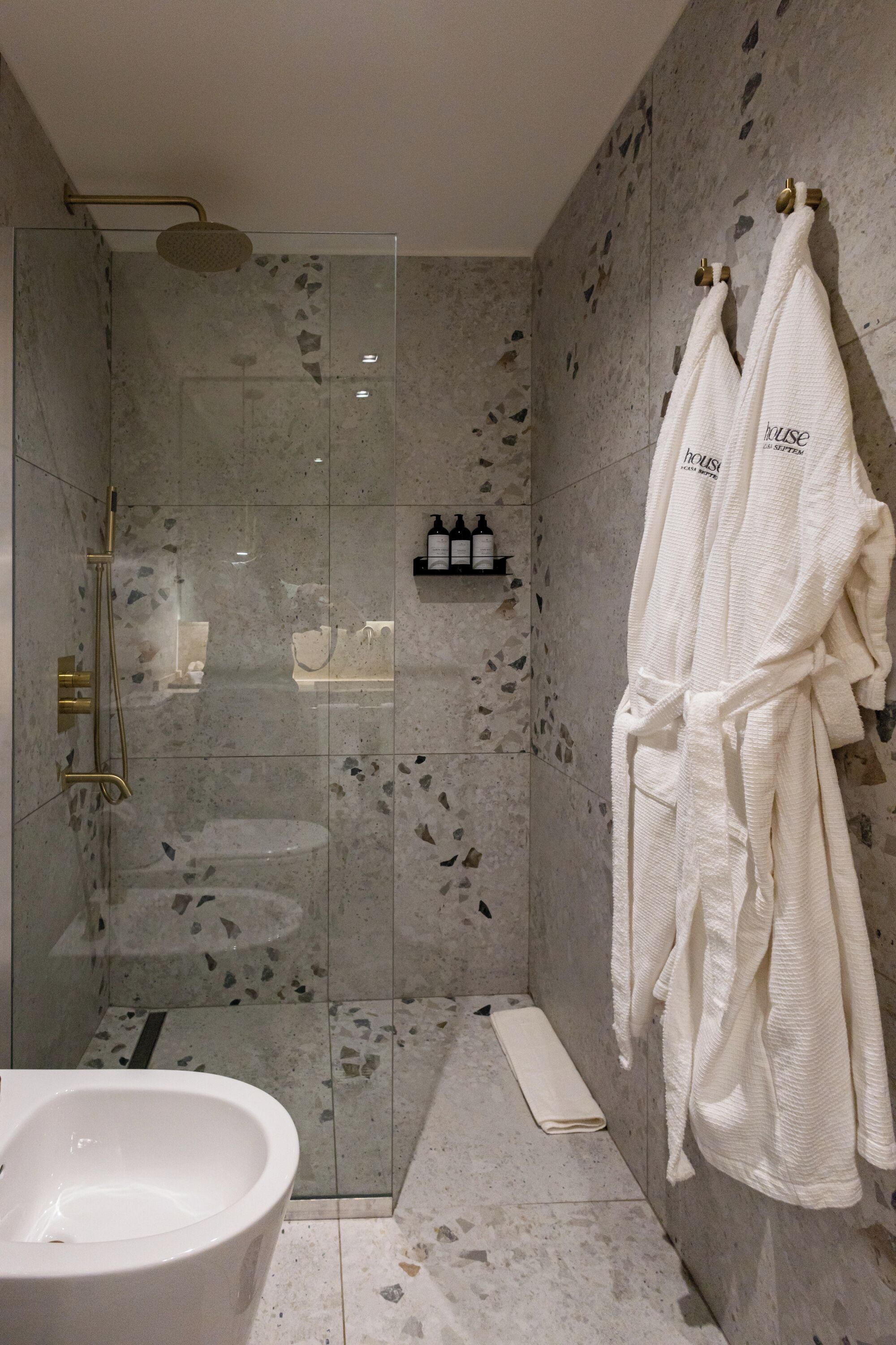 A modern bathroom with a glass-enclosed shower, a freestanding bathtub, and a towel rack with a robe.