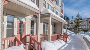A multi-story residential building with a covered front porch and red railings.