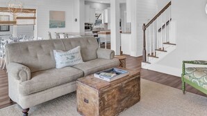 Un salon spacieux comprenant un canapé, une table basse et un escalier menant à l’étage supérieur.