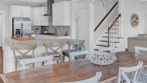 Une cuisine moderne avec des armoires blanches, un réfrigérateur en acier inoxydable et un îlot central en bois doté de sièges.