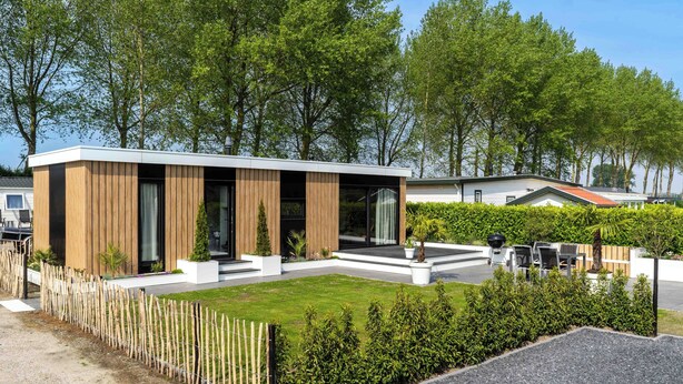 A modern house with a wooden exterior, a well-maintained lawn, and a gravel driveway.