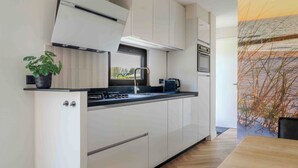 A modern kitchen with white cabinetry, a black countertop, and a window.