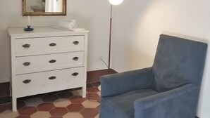 A room with a white dresser, a blue armchair, a floor lamp, and a hexagonal patterned floor. - OPENSPACE APARTMENT WITH GARDEN KM 1.5 FROM THE SEA - OLEANDER (Rosignano Marittimo)