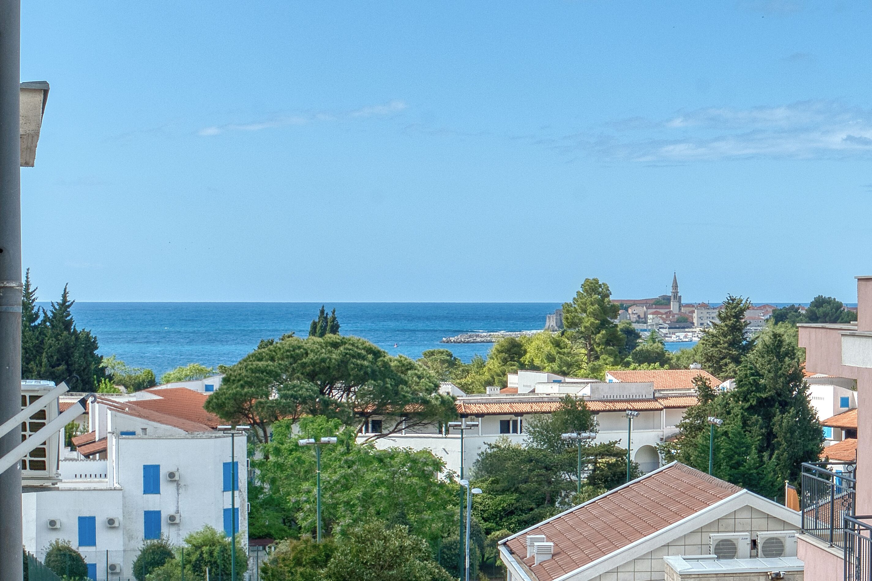 A coastal town with buildings, trees, and a view of the sea.