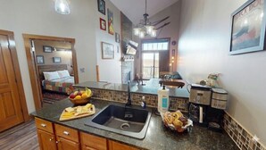 A kitchen with a sink, countertop, and various appliances. There is a dining area with a table and chairs. - AS 434: Penthouse | Ballhooter Views | Cathedral Ceilings | Sleeps 6 (Snowshoe)