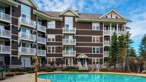 A multi-story residential building with balconies, a swimming pool, and a brick pathway. - AS 434: Penthouse | Ballhooter Views | Cathedral Ceilings | Sleeps 6 (Snowshoe)
