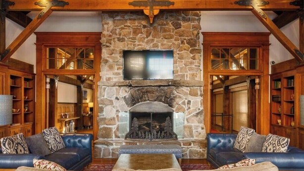 A cozy living room with a stone fireplace, leather sofas, and wooden bookshelves. - AS 434: Penthouse | Ballhooter Views | Cathedral Ceilings | Sleeps 6 (Snowshoe)
