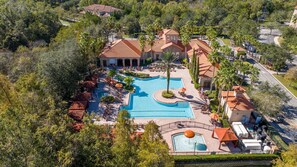 Relax by the large central pool surrounded by sun loungers and umbrellas, amidst lush greenery and palm trees.
