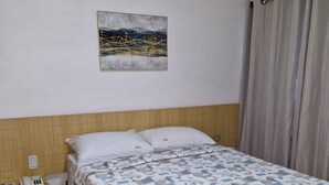 Une chambre d’hôtel avec un lit, une table de chevet avec un téléphone et un tableau au mur.