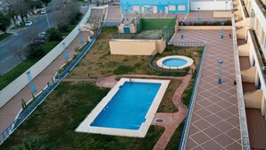 Vista aèria d'una zona residencial amb piscina, un jardí petit i un edifici blau amb àrea de jocs.