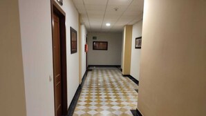 Un passadís amb un dibuix de rajoles de quadres, portes de fusta i quadres a les parets.
