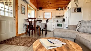 A cozy living room with a wooden coffee table, a grey sofa, and a dining area with wooden chairs and a table.