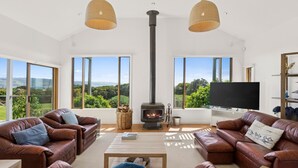 Ein großzügiges Wohnzimmer mit Ledersofas, einem großen Fernseher und einem Kaminofen.