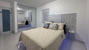 A bedroom with a bed, a mirror, and a wardrobe.