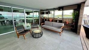 Ein modernes Wohnzimmer mit einer Couch, Sesseln und einem runden Tisch. Es gibt einen Balkon mit Blick auf die Stadt.