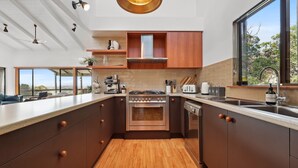 Uma cozinha moderna com uma ilha central, eletrodomésticos de aço inoxidável e armários de madeira.