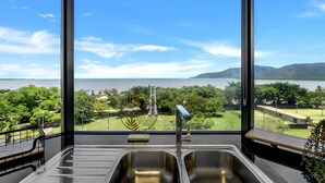 Eine Küche mit großem Fenster, Blick auf einen See und viel Grün.