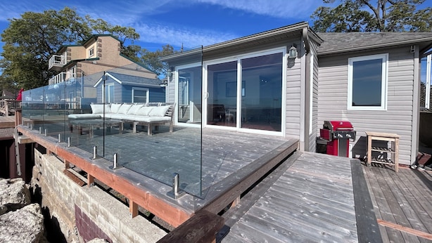 Une terrasse dotée d’une rambarde en verre, d’un banc en bois et d’un espace barbecue.
