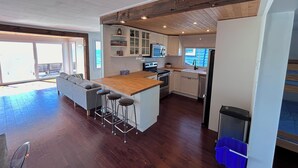 Une cuisine moderne avec un îlot central en bois, des armoires blanches et une grande fenêtre.
