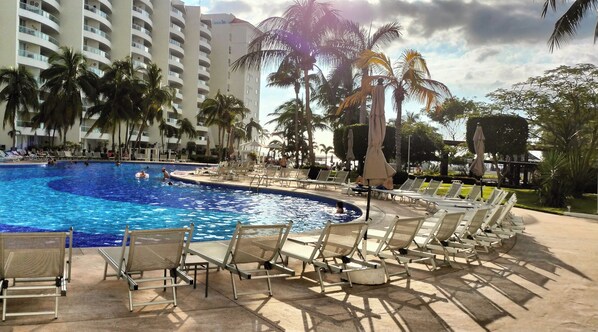 A swimming pool with lounge chairs and palm trees. - Villa Magna - Alcatraz 241 by Kivoya (Nuevo Nayarit)