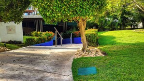 Un ingresso curato con un vialetto in cemento che conduce all'ingresso di un edificio, circondato da prato e siepi ben tenuti.