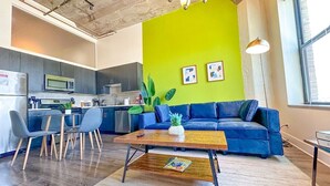 Een moderne woonkamer met een blauwe bank, een houten salontafel en een felgroene accentmuur.