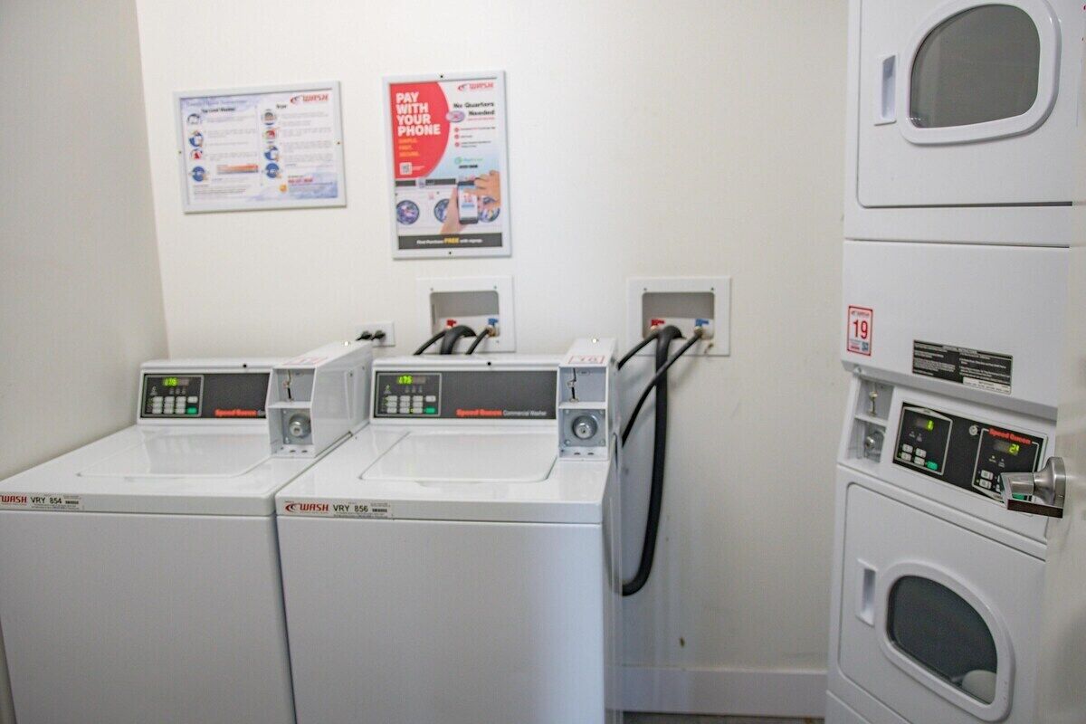 A laundry area with two front-loading washing machines and a stacked dryer.
